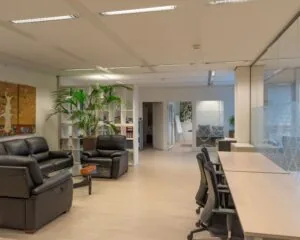 Moderne kantoorruimte aan de Strawinskylaan in Amsterdam met loungehoek, bureaus en glazen wanden.