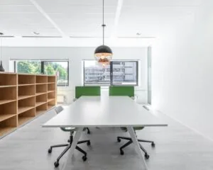 Moderne en lichte kantoorruimte aan de Bavincklaan 7 in Amstelveen met een grote werktafel, groene bureaustoelen en open wandkasten.