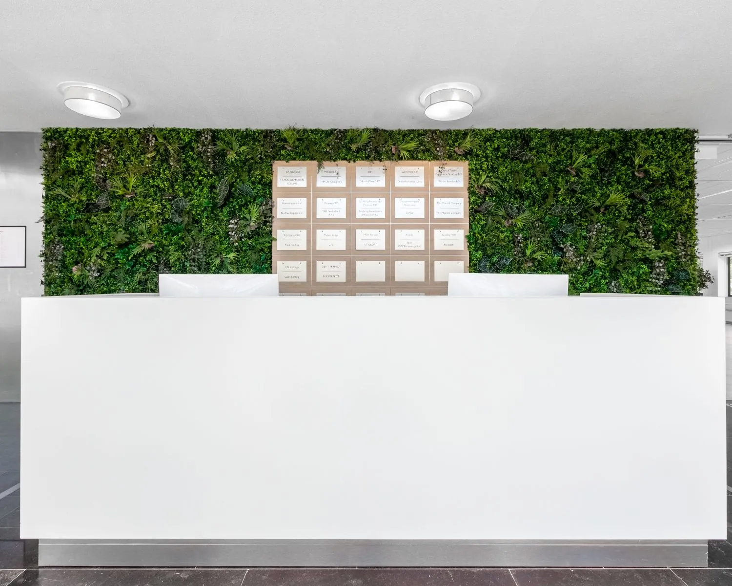 Witte balie in een moderne kantoorruimte aan de Bavincklaan 7 in Amstelveen, met een groene moswand en bedrijfsnaambord op de achtergrond.