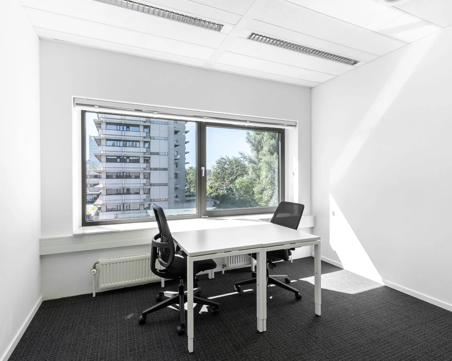 Lichte kantoorruimte aan de Bavincklaan 7 in Amstelveen met twee bureaustoelen en uitzicht op een naastgelegen gebouw.