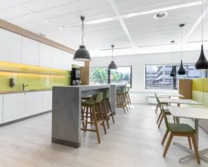 Moderne kantoorruimte in Amstelveen met een open keuken en zithoek met hoge en lage tafels.