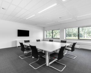 Moderne vergaderruimte in kantoor aan de Bavincklaan 7 in Amstelveen met witte tafel, zwarte stoelen en grote ramen.