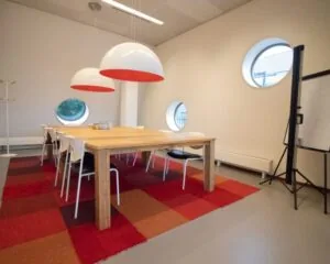 Moderne vergaderruimte aan de Joop Geesinkweg 501 in Amsterdam met houten tafel, designlampen en ronde ramen.