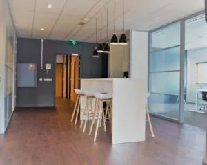 Moderne kantoorruimte aan de Joop Geesinkweg 501 in Amsterdam met hoge tafel, barkrukken en hanglampen.