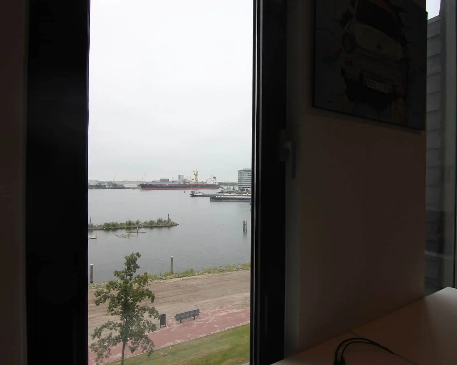 Uitzicht vanuit een kantoorruimte aan de Koivistokade 54 in Amsterdam op het water en een industriële kade.