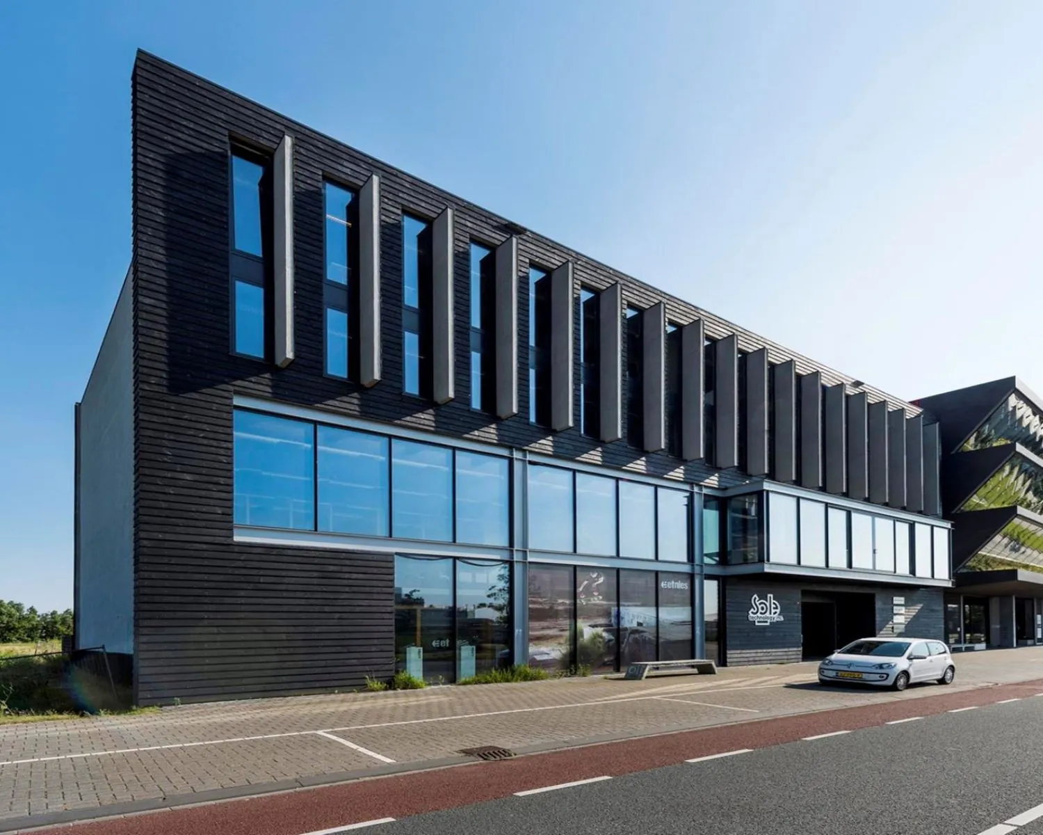 Moderne zwarte kantoorgebouw aan de Koivistokade 54 in Amsterdam met grote ramen en geparkeerde auto.