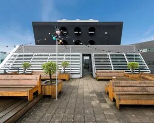 Dakterras met houten zitbanken, plantenbakken en gekleurde sfeerverlichting bij kantoorruimte aan Stationsplein 416 in Schiphol.