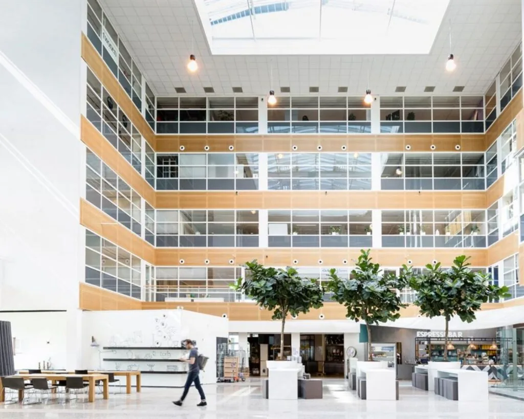 Moderne en lichte entreehal van het kantoorpand aan de Capellalaan 65 in Hoofddorp met zitplekken, groenvoorziening en een espressobar.