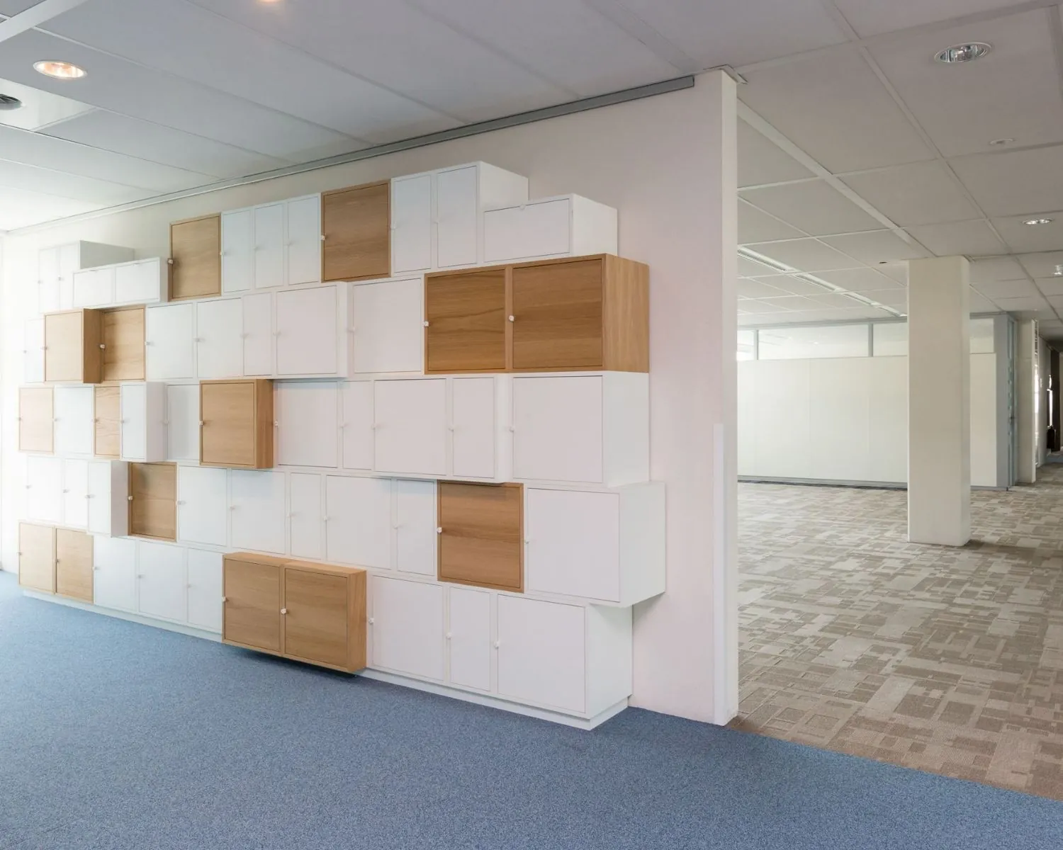 Moderne kantoorruimte aan de Capellalaan 65 in Hoofddorp met een wand van witte en houten opbergkasten.