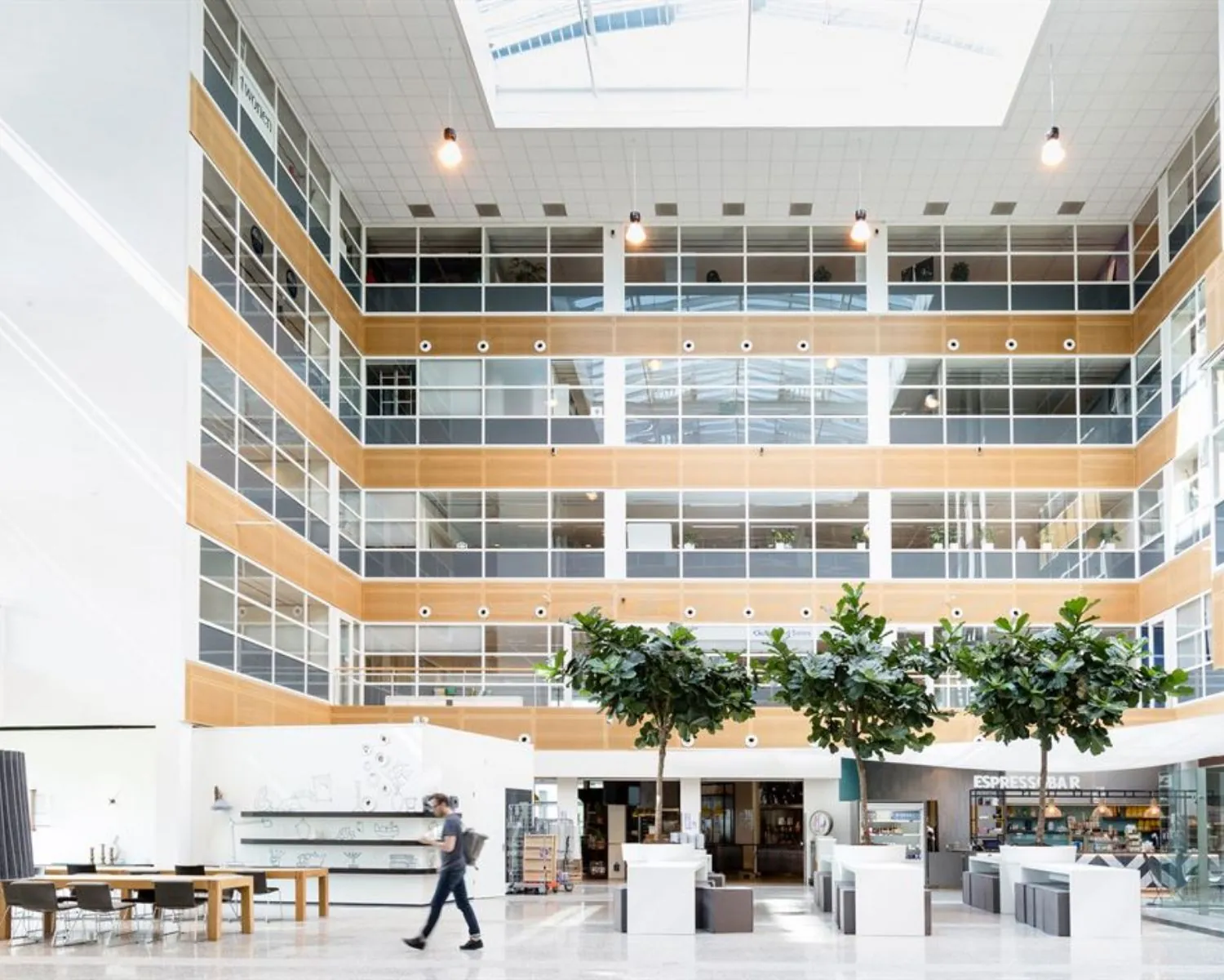 Moderne en lichte entreehal van het kantoorpand aan de Capellalaan 65 in Hoofddorp met zitplekken, groenvoorziening en een espressobar.