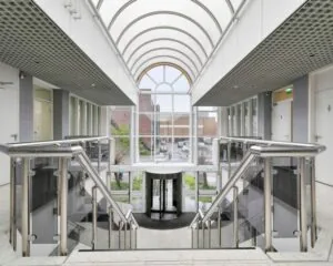 Moderne entreehal met glazen overkapping en dubbele trap in kantoorgebouw aan de Curieweg 7 in Spijkenisse.