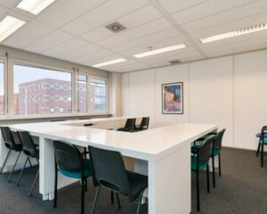Moderne kantoorruimte aan de Curieweg 7 in Spijkenisse met grote witte vergadertafels, meerdere stoelen en veel daglicht.