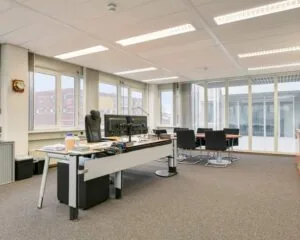 Moderne kantoorruimte aan de Curieweg 7 in Spijkenisse met bureau, vergadertafel en grote raampartijen.