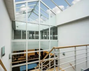 Licht atrium met glazen dak en zicht op meerdere verdiepingen in een modern kantoorgebouw aan de Gyroscoopweg 144 in Amsterdam.
