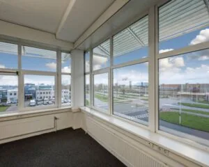 Hoek van een kantoorruimte met grote ramen en uitzicht op het bedrijventerrein aan de Gyroscoopweg 144 in Amsterdam.