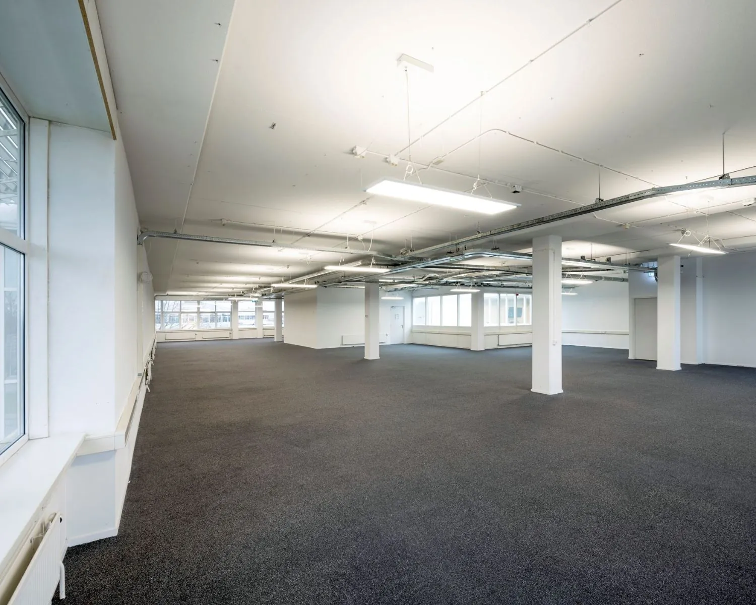 Ruime, leegstaande kantoorruimte met verlichting aan het plafond aan de Gyroscoopweg 144 in Amsterdam.