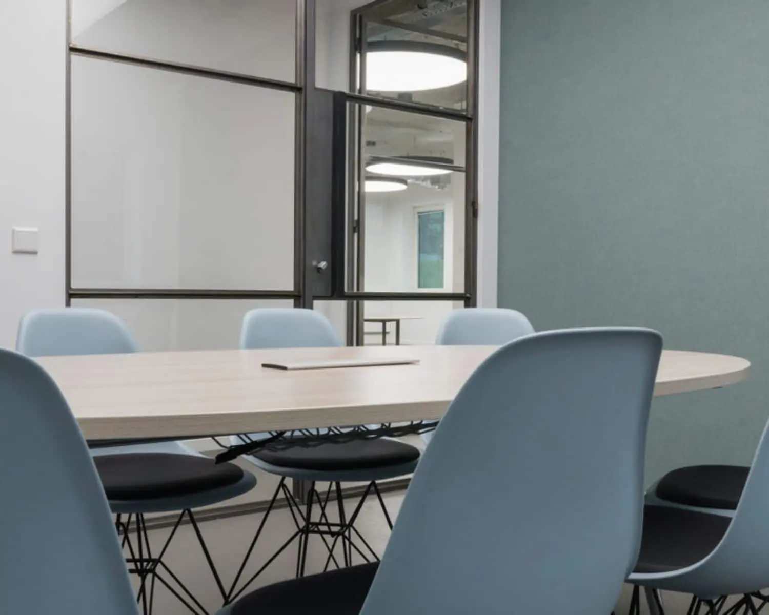 Vergaderruimte met een ovale tafel en lichtblauwe stoelen in een modern kantoor aan de H.J.E. Wenckebachweg 90-108 in Amsterdam.