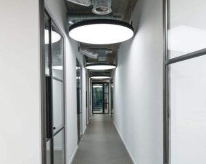 Moderne gang in een kantoorruimte aan de H.J.E. Wenckebachweg 90-108 in Amsterdam met glazen kantoordeuren en ronde plafondlampen.