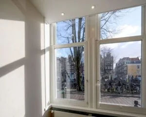 Uitzicht vanuit een lichte kantoorruimte aan de Herengracht in Amsterdam op grachtenpanden en fietsen langs de gracht.