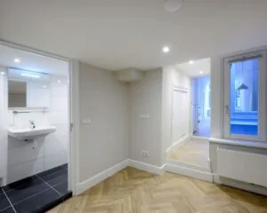 Moderne kantoorruimte aan de Herengracht 352 in Amsterdam met visgraatvloer, wit interieur en aangrenzende badkamer.
