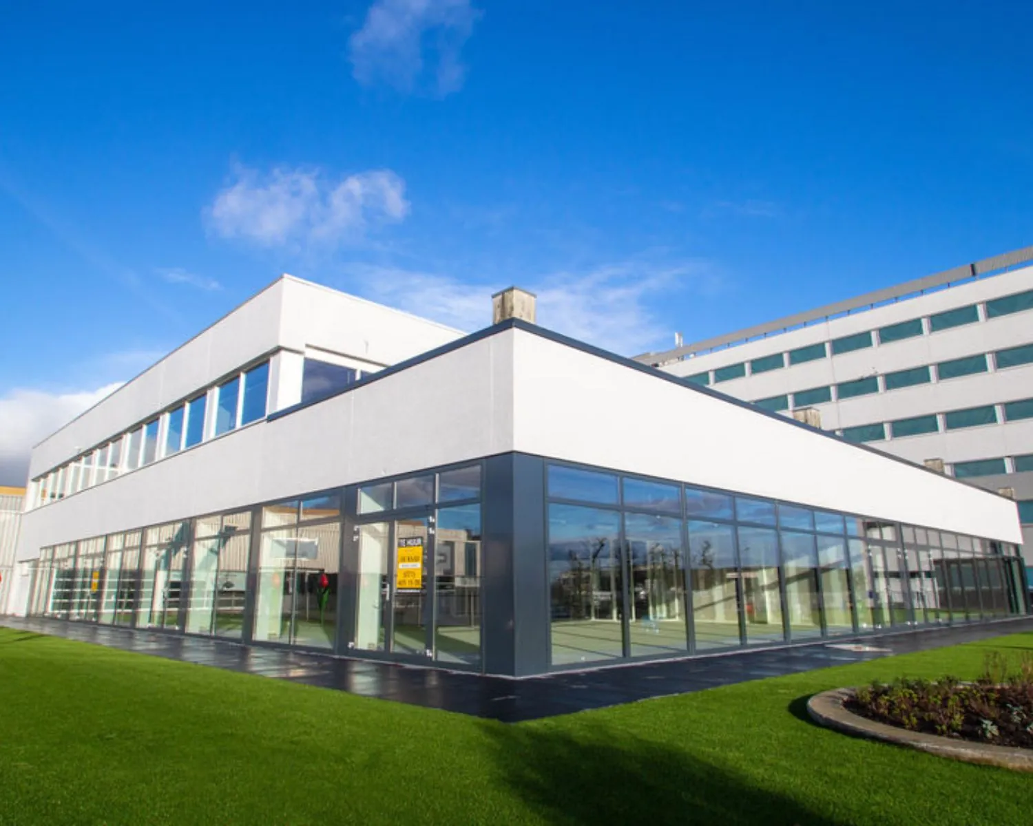 Moderne kantoorruimte aan de Hofmanweg in Haarlem met grote glazen gevel en strak gazon.