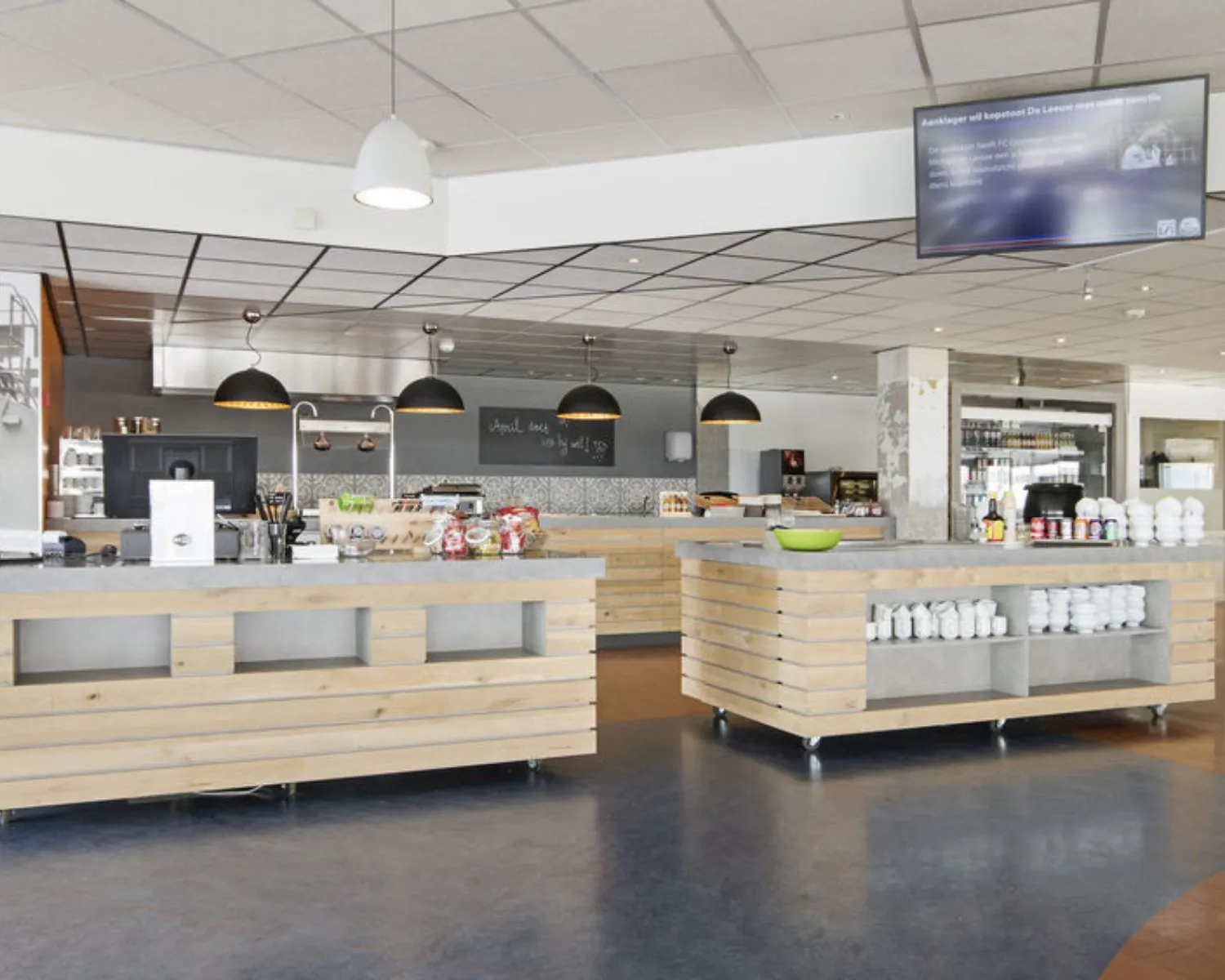 Moderne bedrijfskantine met houten balies en hanglampen in een kantoorruimte aan de Hofmanweg in Haarlem.