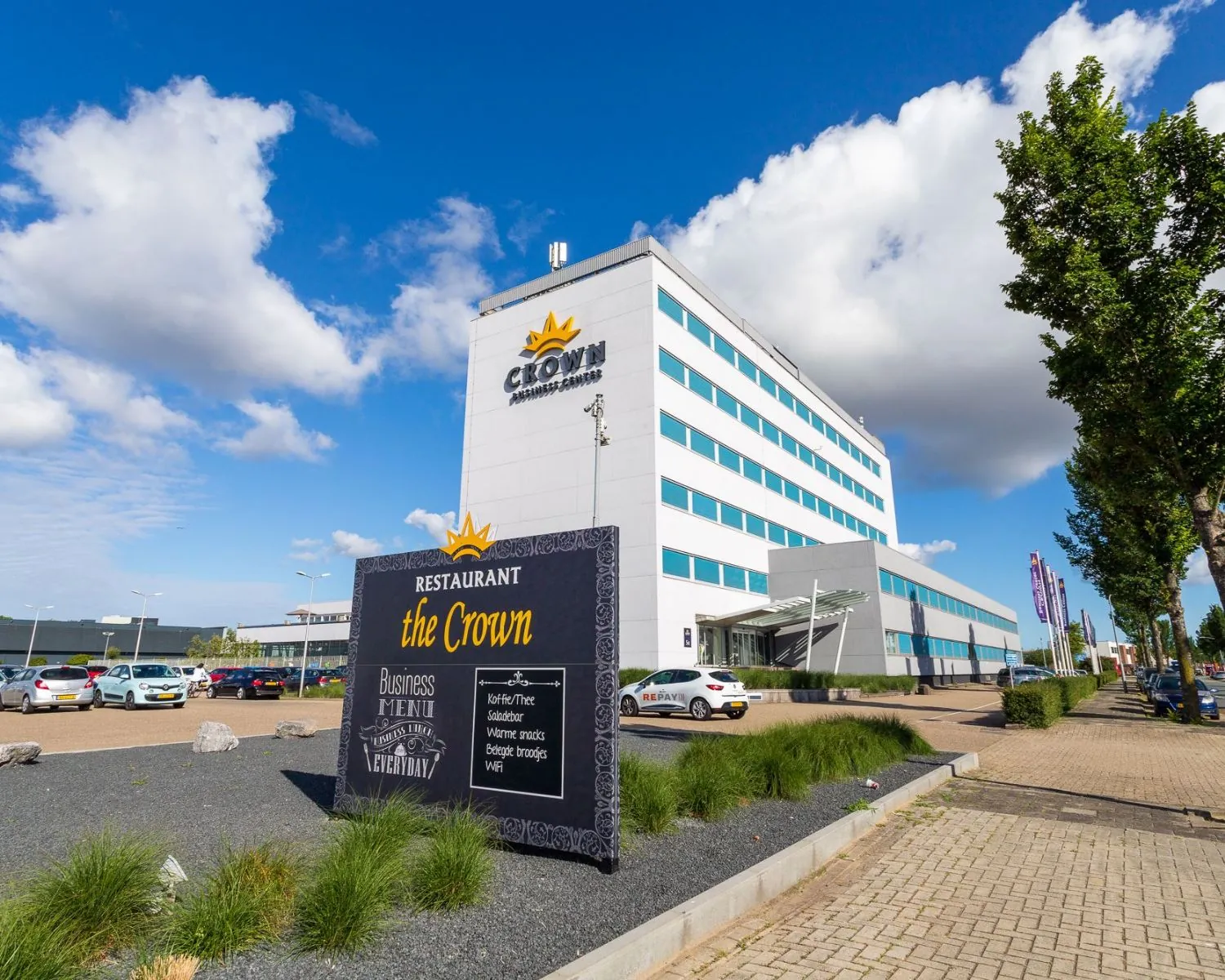 Modern kantoorgebouw aan de Hofmanweg in Haarlem met zicht op restaurant The Crown en parkeerterrein.