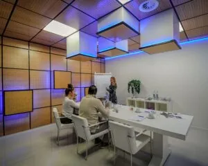 Moderne vergaderruimte aan de Hofmanweg in Haarlem met drie mensen rond een witte tafel en een presentator bij een flip-over.