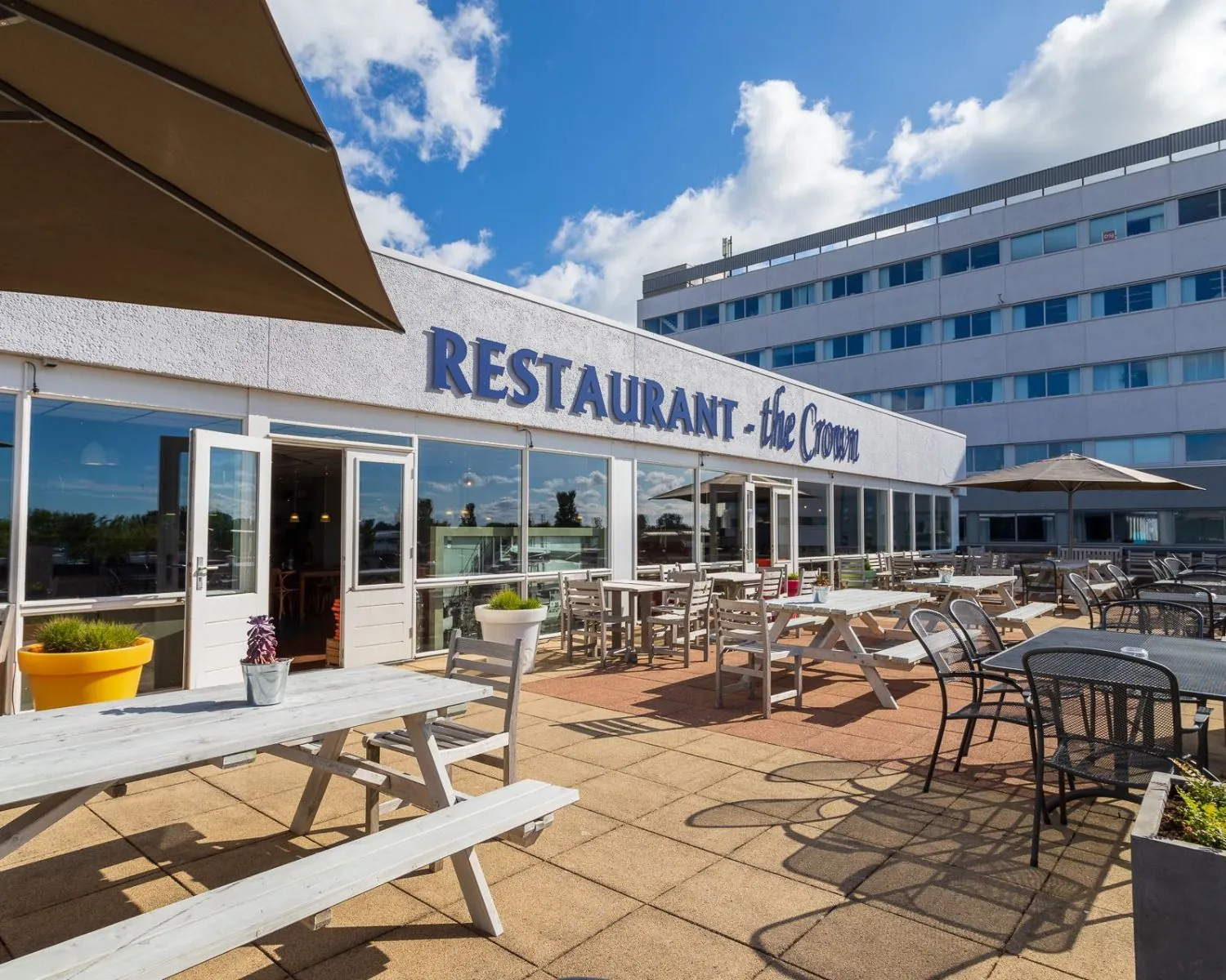 Zonnig terras van Restaurant The Crown aan de Hofmanweg in Haarlem met diverse zitplaatsen en parasols.