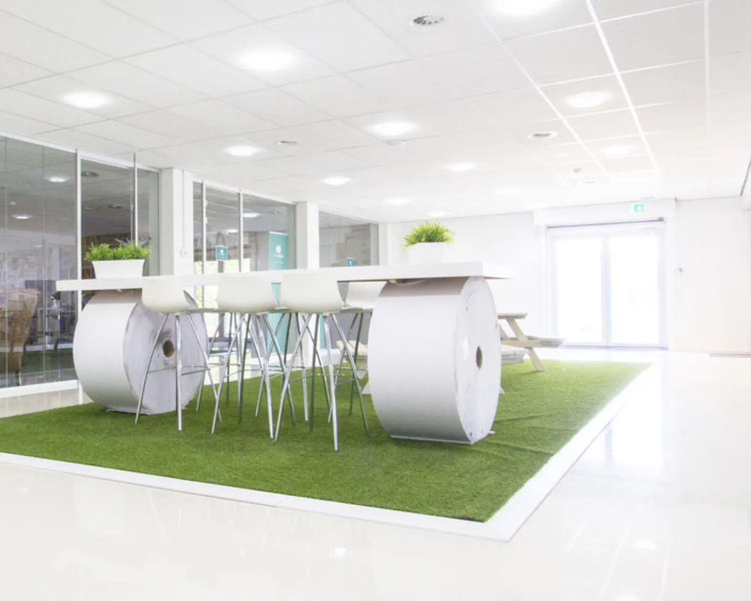 Moderne kantoorruimte aan de Hofmanweg in Haarlem met een creatieve zithoek op kunstgras en een tafel gemaakt van grote papierrollen.