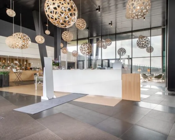 Moderne ontvangsthal van een kantoorruimte aan het Jonkerbosplein 52 in Nijmegen met designverlichting en een strakke witte balie.