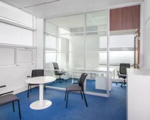 Moderne kantoorruimte met glazen scheidingswand en blauwe vloerbedekking aan het Jonkerbosplein 52 in Nijmegen.