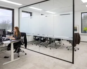 Moderne kantoorruimte aan de Kabelweg 57 in Amsterdam met glazen vergaderruimte en werkplek bij het raam.