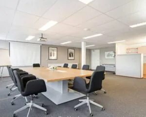 Moderne vergaderruimte met grote houten tafel, zwarte stoelen en presentatievoorzieningen aan de Kanaalweg 33 in Capelle aan den IJssel.