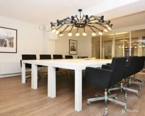 Moderne vergaderruimte aan de Kanaalweg 33 in Capelle aan den IJssel met witte tafel, zwarte stoelen en opvallende hanglamp.