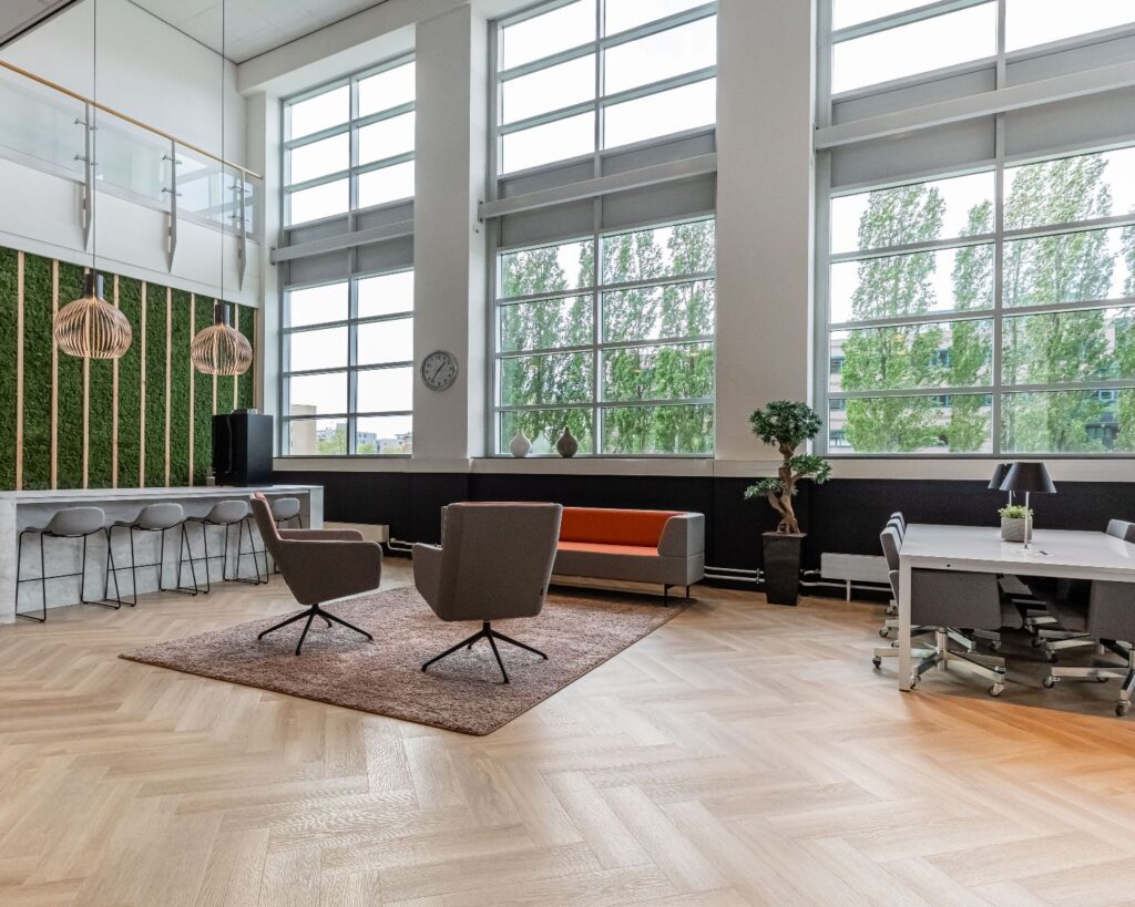 Moderne kantoorruimte aan de Louis Braillelaan 80 in Zoetermeer met hoge ramen, loungegedeelte en werkplekken.
