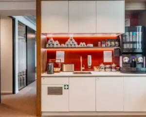 Moderne pantry met koffieautomaat en servies in een kantoorruimte aan de Marten Meesweg 25 in Rotterdam.
