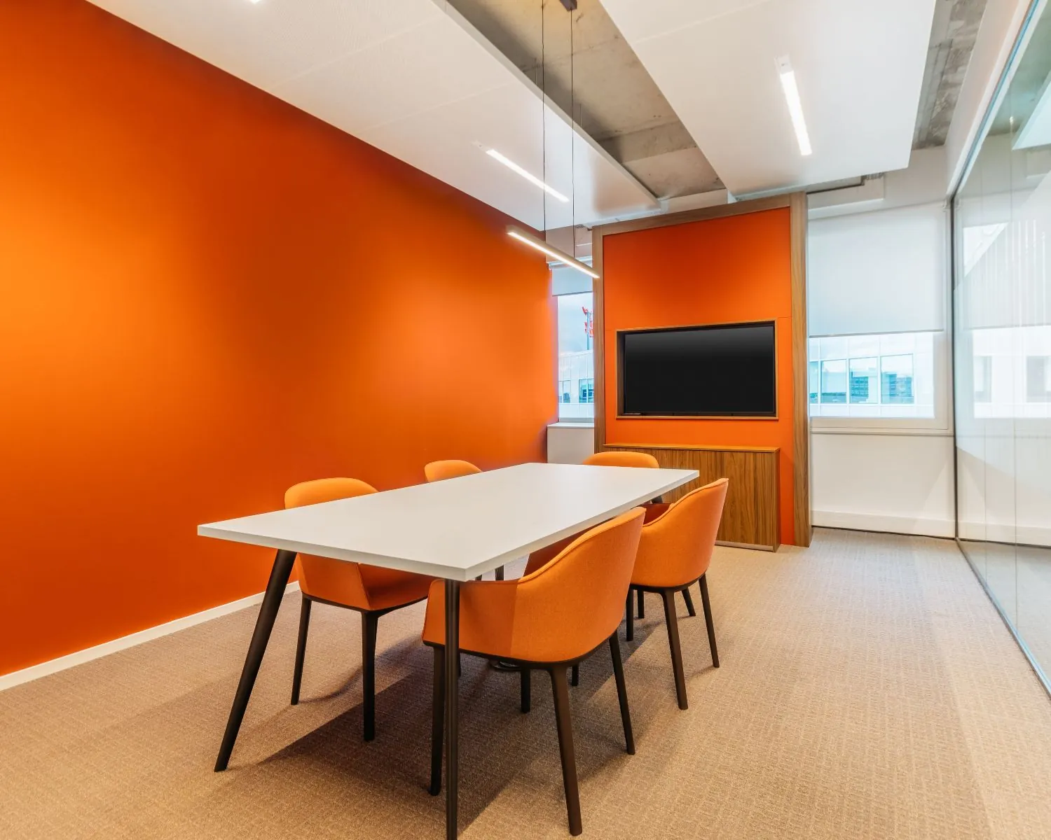 Moderne vergaderruimte aan de Marten Meesweg 25 in Rotterdam met oranje accenten, een witte tafel en een flatscreen.