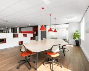 Moderne kantoorruimte aan de Meester B.M. Teldersstraat 7 in Arnhem met vergadertafel, rode accenten en veel natuurlijk licht.