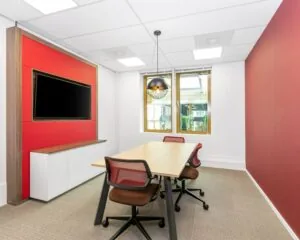 Moderne vergaderruimte in kantoor aan de Meester B.M. Teldersstraat 7 in Arnhem met rode accentmuur, houten tafel en flatscreen.