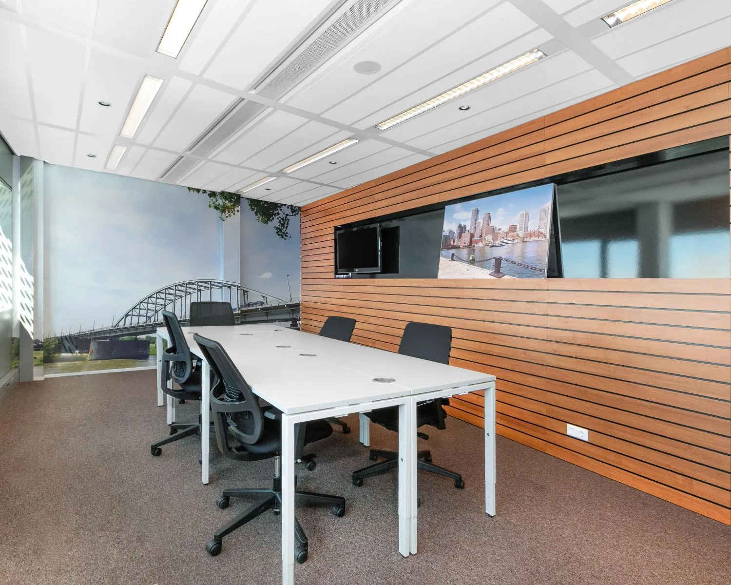 Moderne vergaderruimte aan de Nieuwe Stationsstraat 20 in Arnhem met zes stoelen, wanddecoratie en uitzicht op een brug.