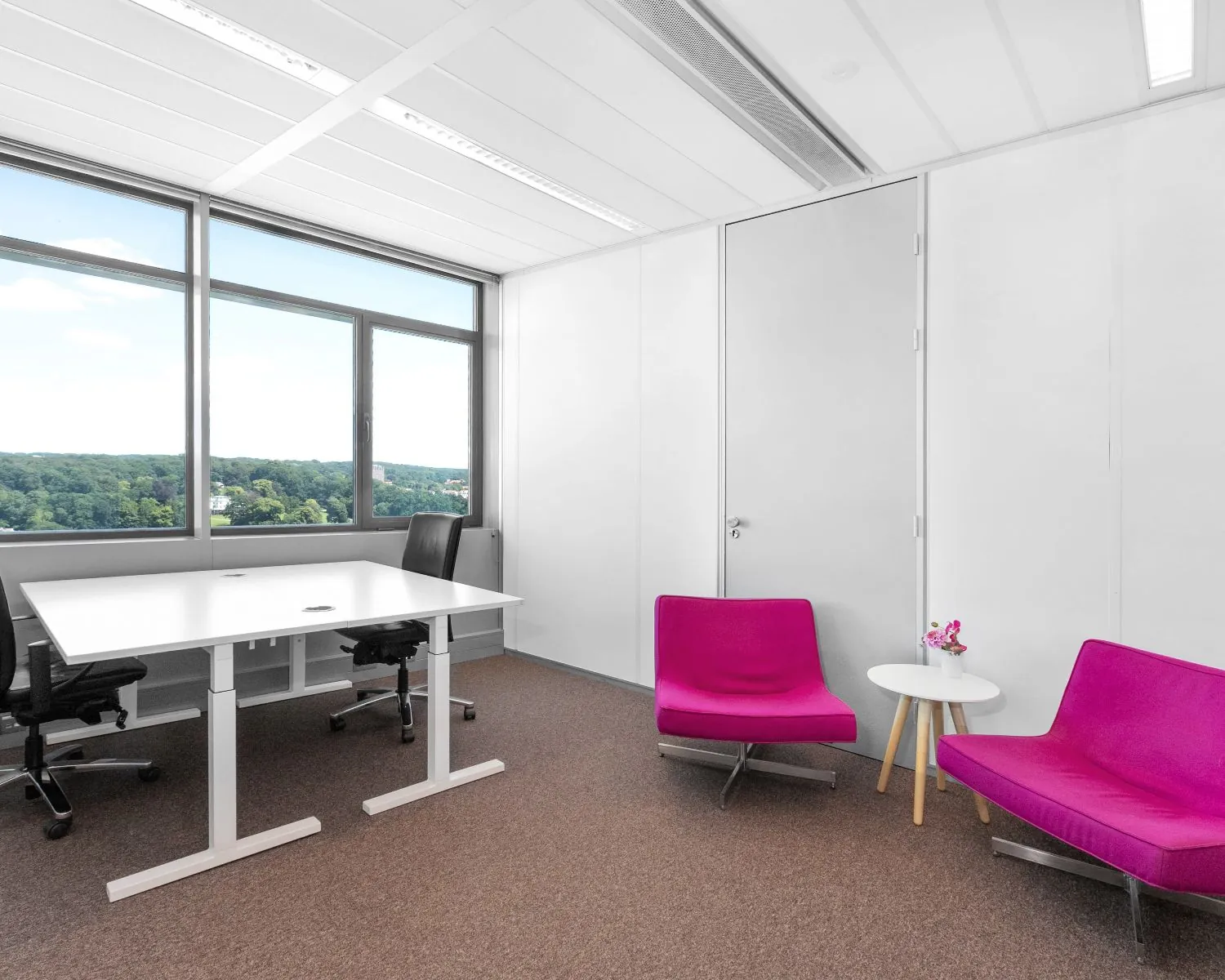 Moderne kantoorruimte aan de Nieuwe Stationsstraat 20 in Arnhem met bureau, stoelen en felroze zithoek.