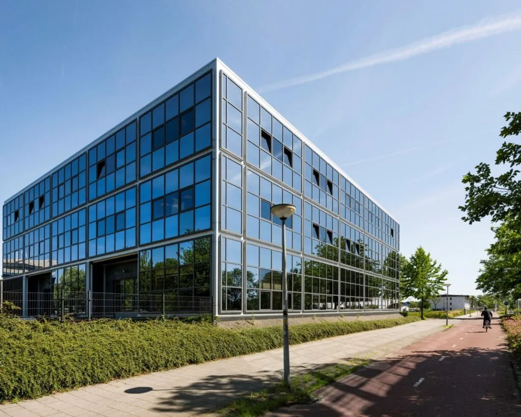 Modern kantoorgebouw met glazen gevel aan de Overschiestraat 180 in Amsterdam, gezien vanaf het fietspad.