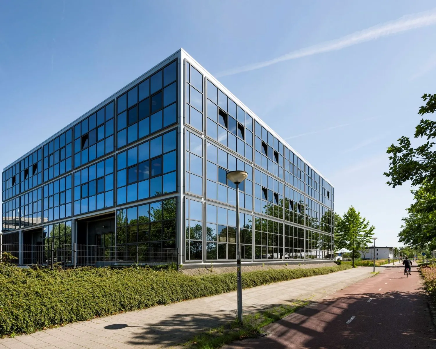 Modern kantoorgebouw met glazen gevel aan de Overschiestraat 180 in Amsterdam, gezien vanaf het fietspad.