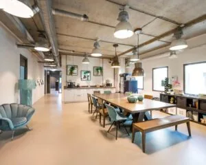Moderne, industrieel ingerichte kantoorruimte met open keuken en grote vergadertafel aan de Overschiestraat 180 in Amsterdam.