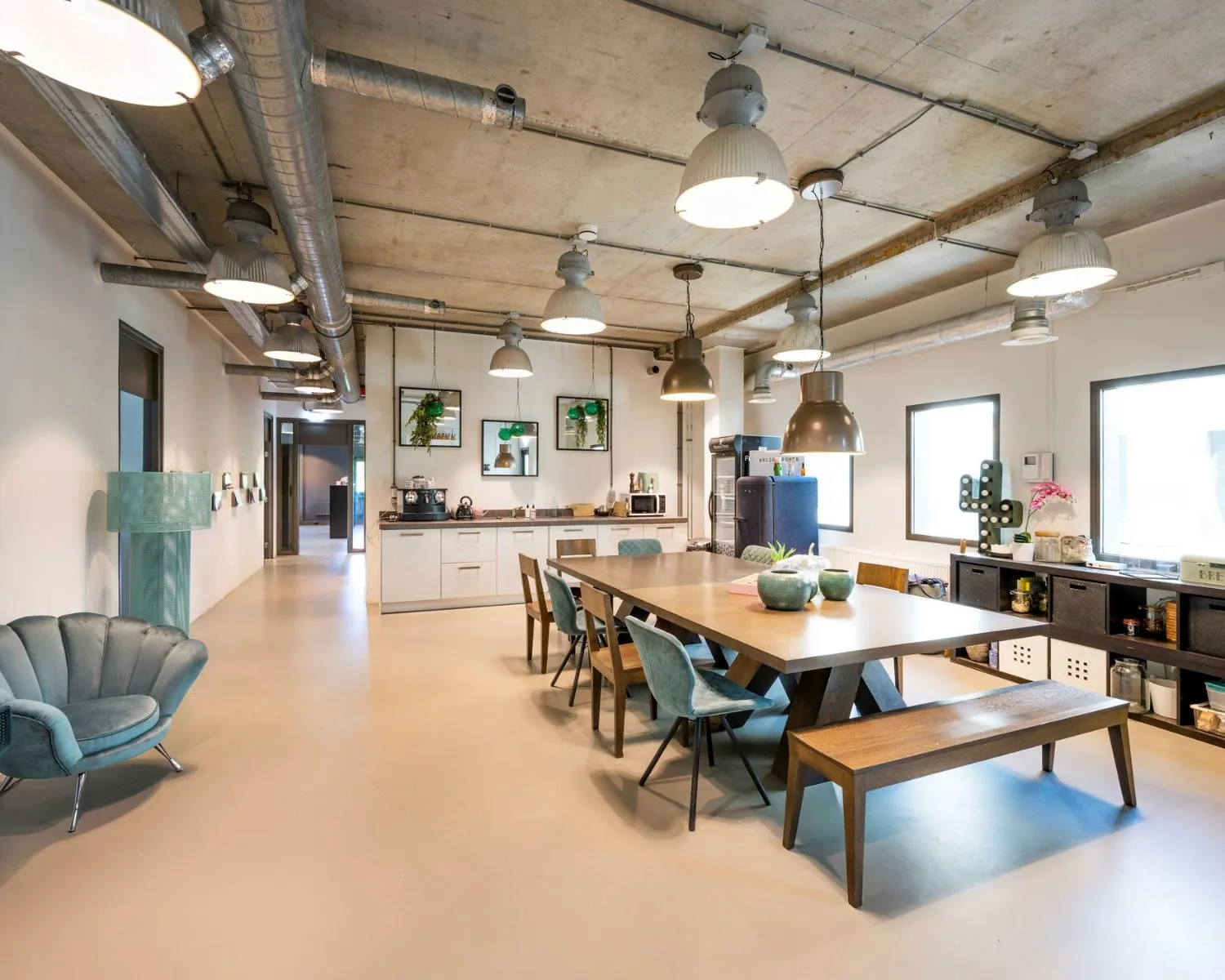 Moderne, industrieel ingerichte kantoorruimte met open keuken en grote vergadertafel aan de Overschiestraat 180 in Amsterdam.