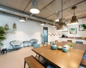 Moderne kantoorruimte aan de Overschiestraat 180 in Amsterdam met een grote houten vergadertafel, loungehoek en open keuken.