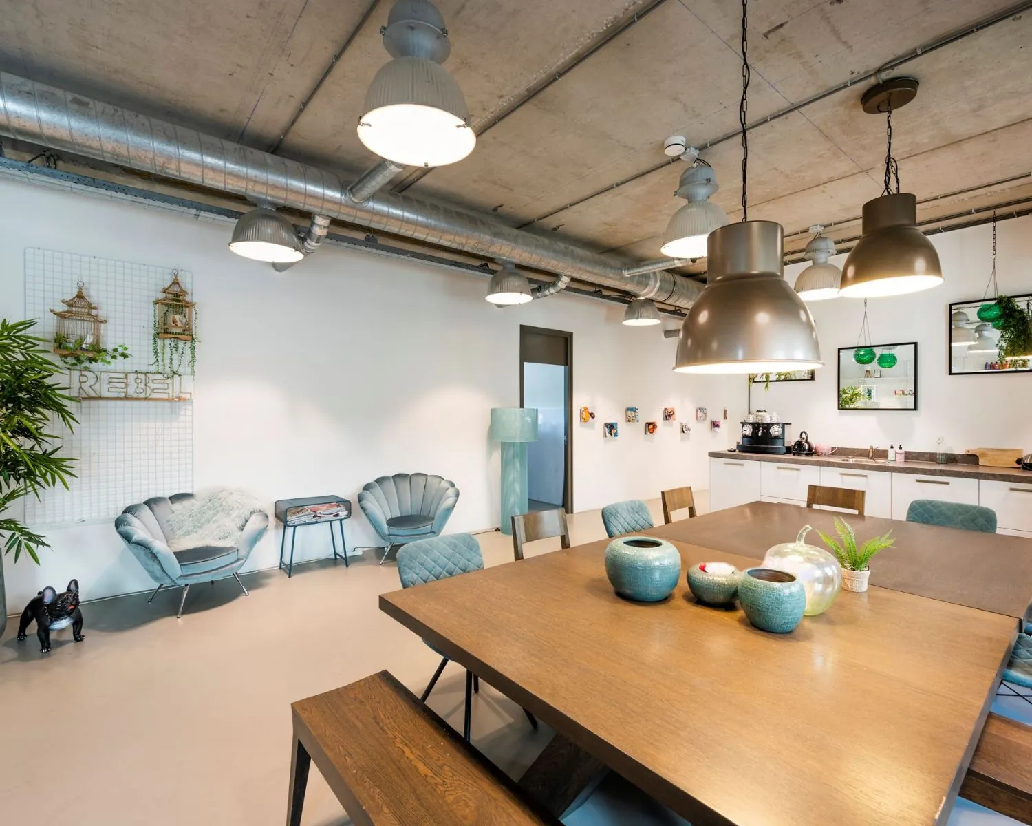 Moderne kantoorruimte aan de Overschiestraat 180 in Amsterdam met een grote houten vergadertafel, loungehoek en open keuken.