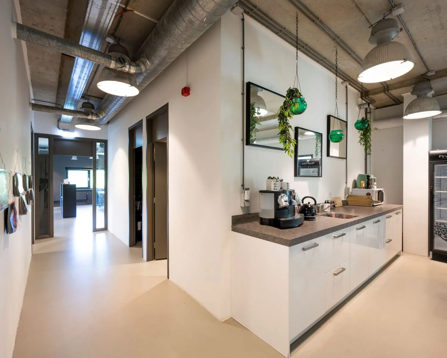 Moderne pantry in een kantoorruimte aan de Overschiestraat 180 in Amsterdam met koffieapparaat, magnetron en hangende planten.