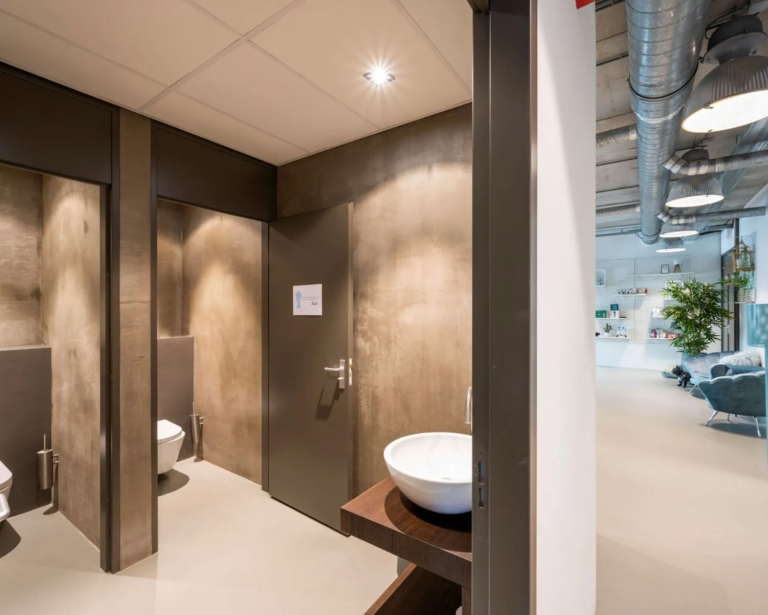 Moderne sanitaire ruimte met betonnen wanden en een wastafel in een kantoorgebouw aan de Overschiestraat 180 in Amsterdam.